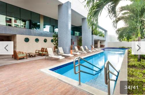 una piscina con sedie e un edificio di Flat no Hotel Beach Class By HOM a Recife