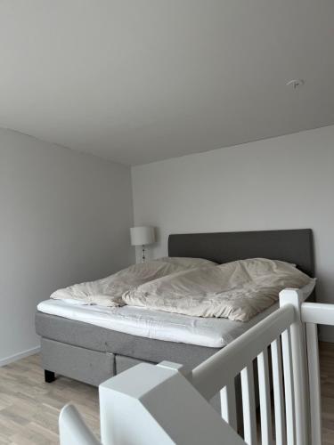 a bed in a bedroom with a white wall at Nybyggd lgh 100m till stranden, 150m till golfbana ,samt gemensam pool och spa in Beddinge