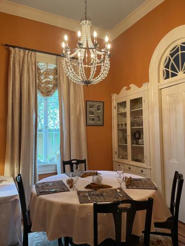 a dining room with a table and a chandelier at The Happy House in New Orleans
