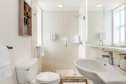 a white bathroom with a toilet and a sink at Aloha Fridays in Miami Beach