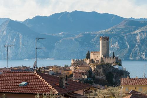 a castle on top of a hill with water and mountains at Appartamenti My Dream in Malcesine