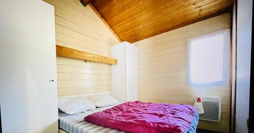 - un petit lit dans une chambre dotée d'un plafond en bois dans l'établissement Chalet climatisé avec vue lac, à Lissac-sur-Couze