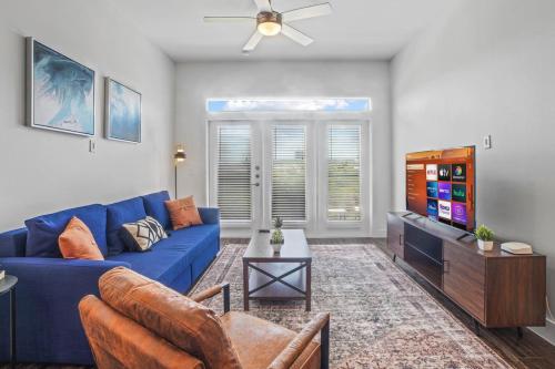 a living room with a blue couch and a tv at Luxurious New Unit 2Bd2Ba Pool, Golf Sim in Austin