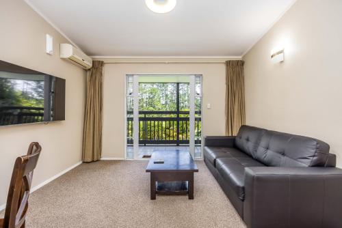 a living room with a leather couch and a table at Northridge Golf Resort in Orewa