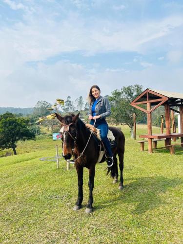 a woman sitting on a horse in a field at Chalé Rústico com Hidromassagem e Piscina in Imaruí
