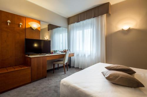 a hotel room with a bed and a desk and a television at Best Western Hotel Turismo in San Martino Buon Albergo