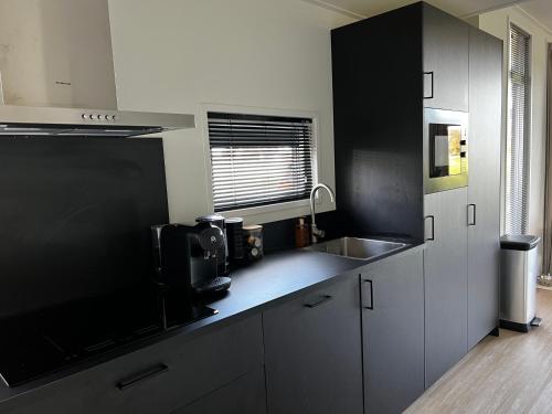 a kitchen with black and white cabinets and a sink at Boshuisje 15 in Haarle