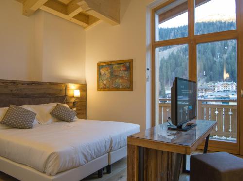 a bedroom with a bed and a television on a table at Hotel Garnì Caminetto in Madonna di Campiglio