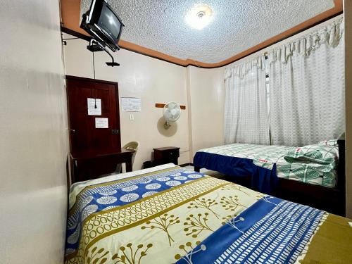 a room with two beds and a tv on the wall at Hostal Amazónico Bello Amanecer in Nueva Loja