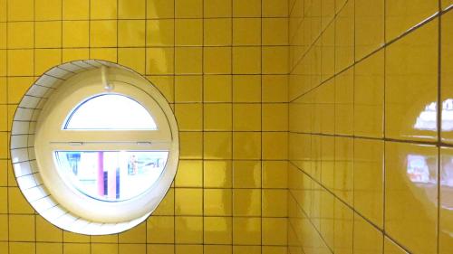 a mirror in a yellow tiled bathroom with a window at Easy&cosy Cityroom in Gelsenkirchen