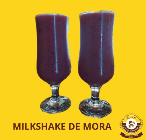 two glasses filled with a purple drink on a yellow background at Alisson Hotel y Restaurant in Monteverde Costa Rica