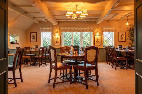 a dining room with tables and chairs and a chandelier at The Old House Inn in Burstow