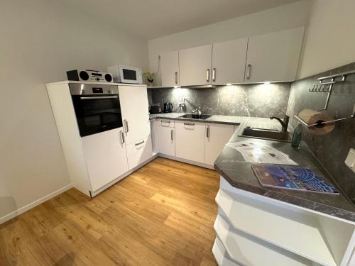 a kitchen with white cabinets and a wooden floor at K14 FeWo - Am Kurpark - Therme in Bad Saarow