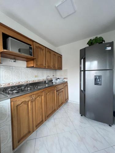 a kitchen with wooden cabinets and a stainless steel refrigerator at Apartamento en Laureles Medellin in Medellín
