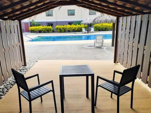 a patio with a table and two chairs and a pool at Survivor Samoa Beach Resort in Falelatai
