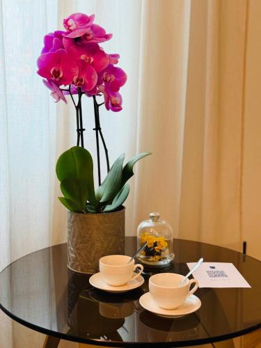 a table with two cups and a vase with flowers at Palazzo CarpeDiem-Prato della Valle in Padova