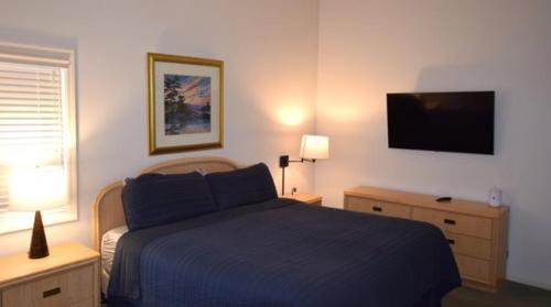 a bedroom with a blue bed and a flat screen tv at CrossWinds Getaway at Shanty Creek in Bellaire