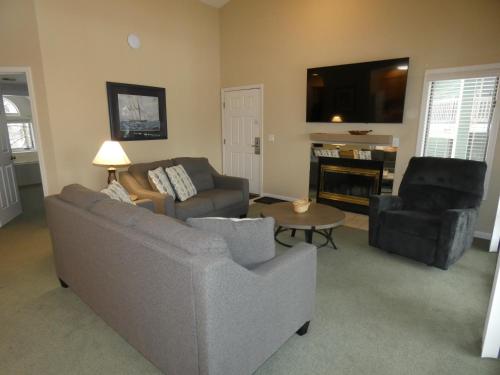 a living room with a couch and chairs and a tv at CrossWinds Getaway at Shanty Creek in Bellaire