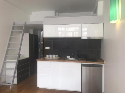 une cuisine avec des placards blancs et une échelle dans l'établissement St Marc appartement 4 Personnes au Centre de Paris, à Paris
