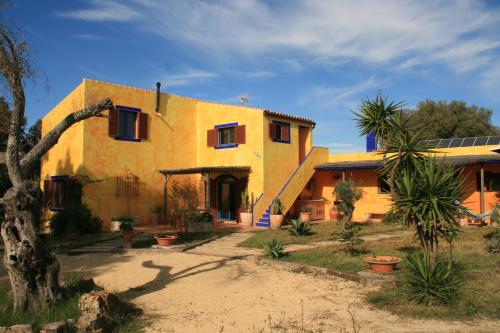 ein großes gelbes Haus mit einem Baum davor in der Unterkunft El Vuelo de la Libélula in Barbate