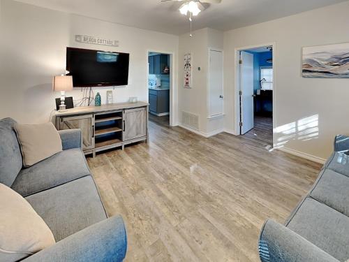 a living room with a couch and a flat screen tv at The Charming Cozy Cottage in Rockport