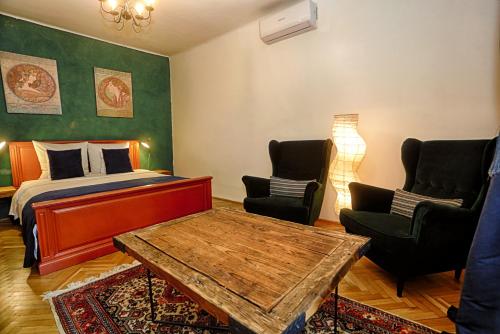 a bedroom with a bed and two chairs and a table at Union Square Apartment by NUX in Cluj-Napoca