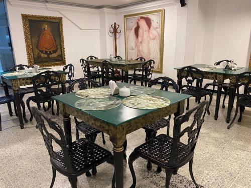a dining room with tables and chairs and a painting at TAMA Hotel Granada Real Cali in Cali