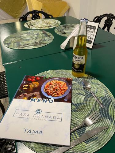 a bottle of beer sitting on a table with plates of food at TAMA Hotel Granada Real Cali in Cali