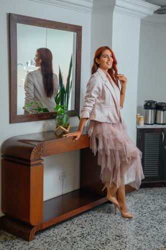 a woman leaning on a desk in front of a mirror at TAMA Hotel Granada Real Cali in Cali