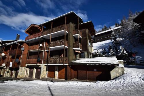 un bâtiment avec de la neige sur le sol devant lui dans l'établissement Chalet Le Becoin - CHALET MITOYEN 10/12 pers - 100m des pistes SAUNA- WIFI - PLAGNE 1800 MAE-6654, à Aime La Plagne