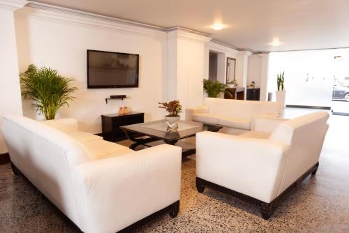 a living room with white furniture and a flat screen tv at TAMA Hotel Granada Real Cali in Cali