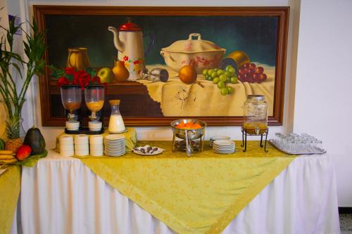 a table with food and a painting of fruits on it at TAMA Hotel Granada Real Cali in Cali
