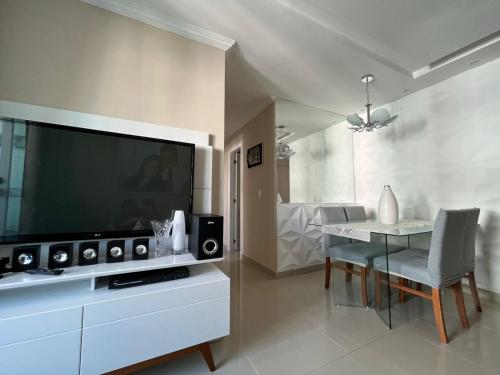 ein Wohnzimmer mit einem großen TV und einem Tisch in der Unterkunft Piscina, Campo, Quadra poliesportiva e Salão festa in Paulista