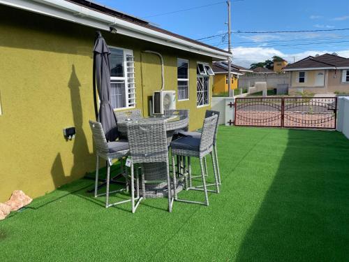 a patio with a table and chairs and an umbrella at Harbour Oasis Retreat - Charming 2 Bedroom House in Old Harbour