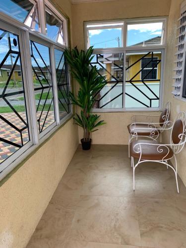 a balcony with a bench and a plant and windows at Harbour Oasis Retreat - Charming 2 Bedroom House in Old Harbour