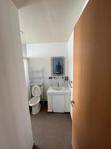 a white bathroom with a toilet and a sink at Súperanfitrión Coyoacán El Alebrije in Mexico City