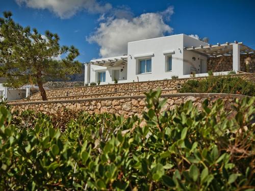 a white house on a hill with a stone wall at Alsalos villas in Amoopi