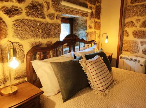 a bedroom with a wooden bed with pillows on it at Castrum Houses - Casa da Curveirinha - Jacuzzi in Melgaço