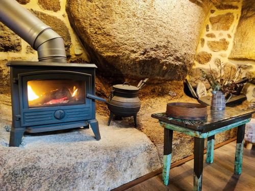 a wood stove in a room with a table at Castrum Houses - Casa da Curveirinha - Jacuzzi in Melgaço