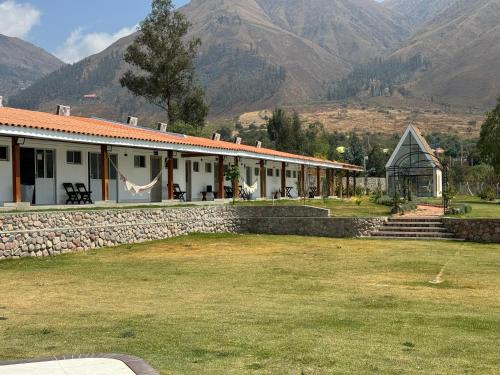 a building with a stone wall and mountains in the background at Hotel Boutique La Caballeriza in Quillacollo