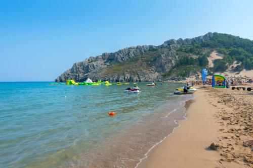 a beach with a group of people in the water at Elefteria Apts & Suites in Kolimbia