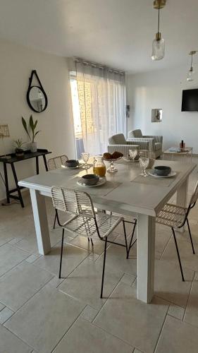 - une grande table blanche avec des chaises dans le salon dans l'établissement Heol, à Saint-Igneuc