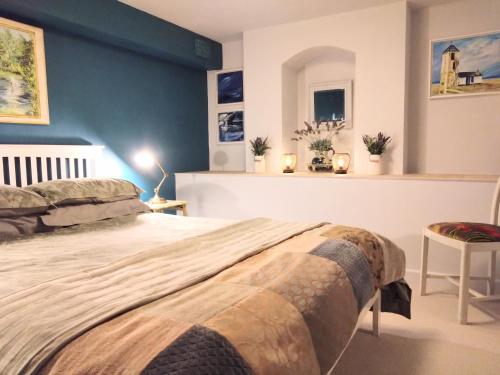 a bedroom with a large bed with a blue wall at Beachfront Studio Apartment in Felixstowe