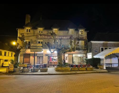 un grand bâtiment avec des panneaux sur une rue la nuit dans l'établissement Auberge de Lanouaille, à Lanouaille