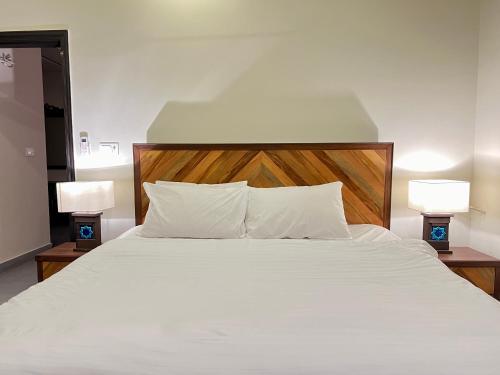 a bedroom with a white bed with two lamps at 2 Bedroom Appartment Near Airport & Moterway in Islamabad