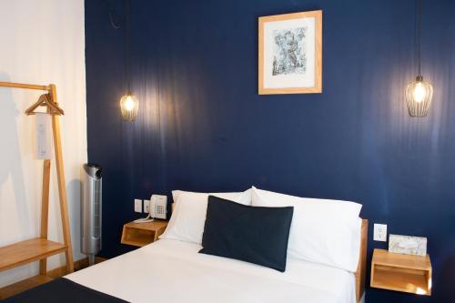 a bedroom with blue walls and a bed with white pillows at Romance City Hotel in Morelia