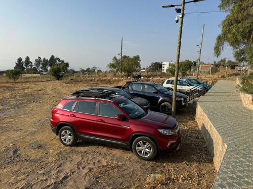 a red suv parked next to a row of parked cars at Hotel Boutique La Caballeriza in Quillacollo
