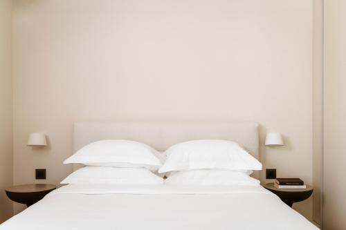 a white bed with two pillows and two tables at Likno Athens in Athens