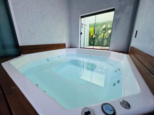 a large white bath tub in a room with a window at Casa em Bombinhas in Bombinhas