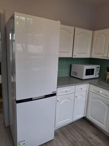 a white kitchen with a refrigerator and a microwave at Kilvington Crib in Sheffield